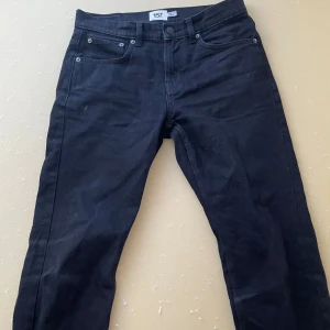 Svarta jeansbyxor från 157 - Svarta jeansbyxor från 157 med klassisk femficksdesign och raka ben. Byxorna har normal passform och stängs med dragkedja och knapp. Perfekta för en stilren och enkel look.