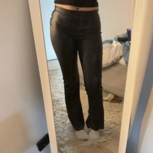 Svarta skinnbyxor med bootcut - Säljer ett par svarta skinnbyxor med bootcut-modell. Byxorna har låg midja och sitter tight upptill med utsvängda ben. Perfekta för dig som vill ha en trendig och edgy look.