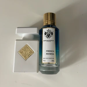 Parfymduo: Mancera French Riviera & vit flaska med gulddetalj - Säljer två exklusiva parfymer: Mancera French Riviera i blå glasflaska med guldfärgat lock (60 ml) och en elegant vit parfymflaska med dekorativ gulddetalj. Perfekt för dig som gillar lyxiga dofter och snygg design.