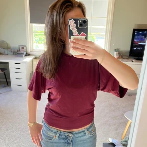 Vinröd t-shirt - En enkel vinröd t-shirt med rund halsringning och korta ärmar. T-shirten har en normal passform och är tillverkad i ett mjukt bomullsmaterial. Perfekt till jeans eller shorts för en avslappnad stil.