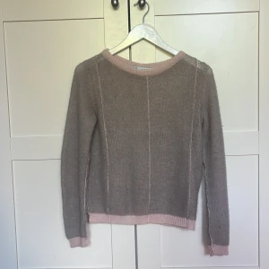Beige stickad tröja med rosa detaljer från Zara - Säljer en supersnygg grå stickad tröja från Zara med ljusrosa ribbade kanter vid hals, ärmslut och nederkant. Tröjan har lång ärm och en enkel, rak passform. Storlek S. Knappt använd. Skriv för frågor! 
