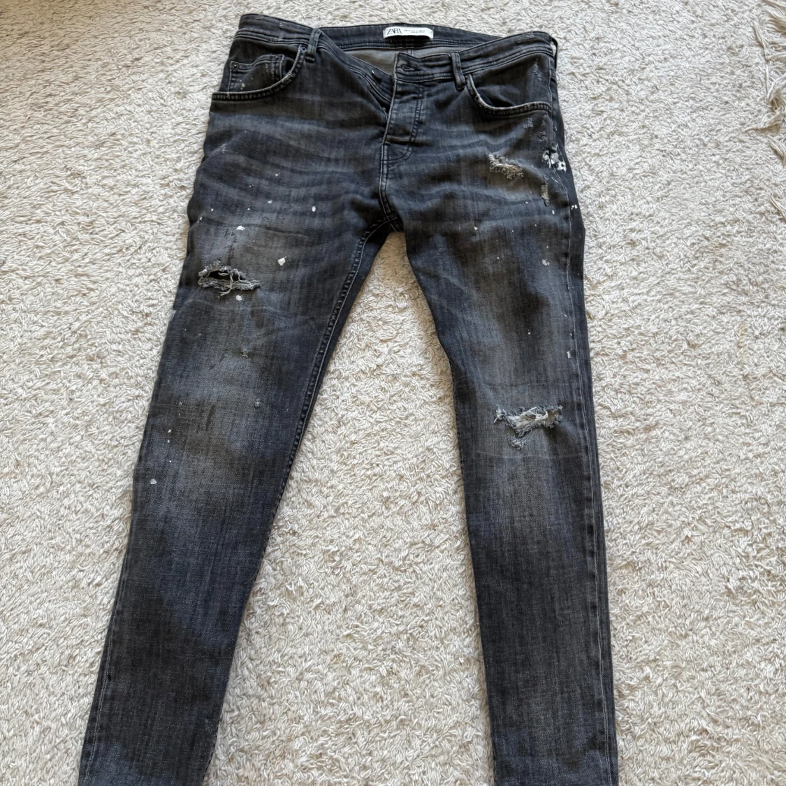 Svarta slitna jeans med färgstänk