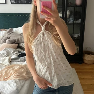 Vit halterneck topp med broderade detaljer - Säljer en söt vit halterneck topp med små broderade gulddetaljer. Toppen knyts i nacken och har öppen rygg. Från Zara, storlek XS❣️