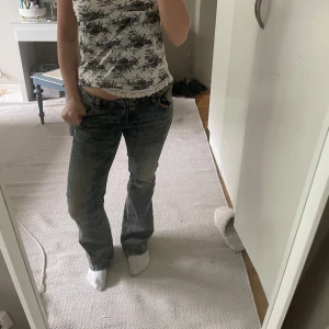 Lågmidjade jeans - Säljer ett par grå/blåa bootcut jeans från HM med klassiska fickor och snygg detalj med kedjan. Jeansen har normal passform och har lågmidja. Använda 2 gnr🩵🤍