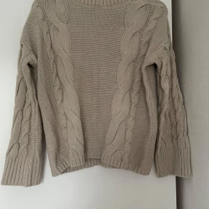 Beige stickad tröja med flätmönster - Säljer en beige stickad tröja med grovt flätmönster både fram och på ärmarna. 