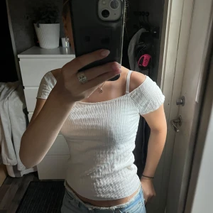 Vit ribbad offshoulder topp XS - Supersöt vit topp från 157 i storlek XS. Modellen är offshoulder med korta ärmar och har en ribbad, stretchig struktur som sitter snyggt och framhäver figuren. Perfekt till jeans eller kjol för en fräsch och trendig look.