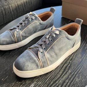 Grå sneakers från Christian Louboutin - Snygga grå sneakers från Christian Louboutin med den ikoniska röda sulan. Skorna har snörning och är tillverkade i mocka med en stilren design. Perfekta för den som vill ha en touch av lyx i vardagen. Pris kan diskuteras‼️OBS. Lite trasig på insidan av hälen på båda  skorna, dock inget som syns eller käns vid andvändning‼️