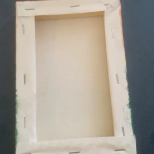 Tavla - Det här är ingen bok, utan en målning på duk. Motivet visar en landsväg som slingrar sig genom grönskande natur mot ett hus, med ett träd i förgrunden och berg i bakgrunden under en orange himmel. Perfekt för dig som gillar konst och vill ha något unikt på väggen. Gjord på egen hand, tog cirka 1 timme.