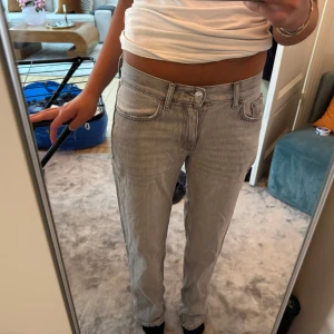 Grå raka jeans från Levis - Säljer ett par grå jeans från Levis med klassisk femficksdesign och raka ben. Jeansen har normal passform och midwaist, med snyggt slitna detaljer och silverfärgad knapp. Perfekt för dig som gillar en clean och chill stil.