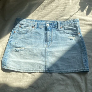 Ljusblå jeanskjol från Stradivarius - Snygg ljusblå jeanskjol från Stradivarius med slitna detaljer framtill. Kjolen har bälteshällor, knapp och dragkedja samt två bakfickor med cool söm. Perfekt för dig som gillar en chill och trendig look❣️