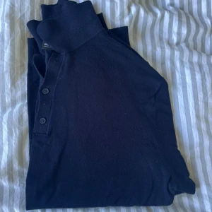 Blå stickad pikétröja Only & Sons - Blå stickad pikétröja från Only & Sons i storlek L. Tröjan har klassisk krage, tre blåa knappar framtill och långärmade ärmar. Materialet är mjukt och stickat, perfekt för dig som gillar stilren och enkel design. 