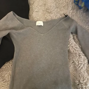 Grå ribbad långärmad tröja V-ringad - Säljer en grå ribbad långärmad tröja från H&M med snygg v-ringad hals. Tröjan har en slim passform och är perfekt för dig som gillar stilrena och enkla plagg. Materialet är mjukt och stretchigt, vilket gör den skön att bära hela dagen. Storlek M men är mer som en storlek S