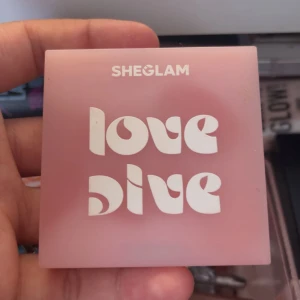 SHEGLAM Love Dive rouge i stark rosa - Snyggt puderrouge från SHEGLAM i färgen 'Don't Pink Twice'. Kommer i en stilren, ljusrosa förpackning med coolt retro-tryck. Rouget är intensivt rosa och har en pressad design i pudret. Perfekt för att ge kinderna en pop av färg.