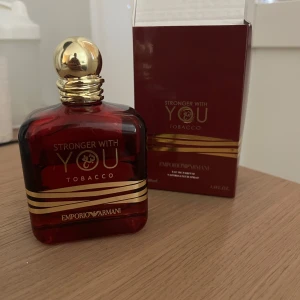 Emporio Armani Stronger With You Tobacco - Emporio Armani Stronger With You Tobacco EdP i en lyxig mörkröd glasflaska med guldiga detaljer och rund guldfärgad kork. Flaskan rymmer 100 ml och har en elegant, maskulin design. Doften är kryddig och varm med tydliga tobaksnoter.