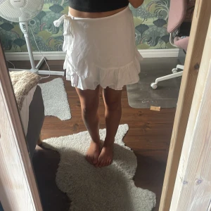 Vit omlottkjol med volang från Stradivarius - Supersöt vit omlottkjol från Stradivarius i storlek XS. Kjolen har volangkant och knytband i midjan! Den är aldrig använd utan bara provad!💕