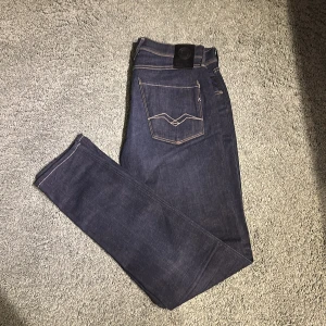 Replay Anbass jeans mörkblå strl 33 - Snygga mörkblå Replay Anbass jeans i klassisk straight fit. Jeansen har kontrastsömmar, fem fickor och cool detalj på bakfickan. Materialet är slitstarkt jeans och passformen är normal. Perfekta för dig som gillar stilrena och tidlösa jeans. Och dom är näst intill oanvända 