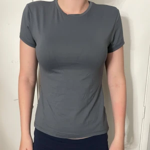 Mörkgrå basic t-shirt - En stilren mörkgrå t-shirt med rund hals och korta ärmar. Den är väldigt fin och sitter bra o formar kroppen jättefint, knappt använd.