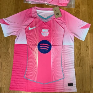 Rosa FC Barcelona fotbollströja Nike - Snygg FC Barcelona fotbollströja från Nike i en fräsch rosa färg med vita och ljusblå detaljer.