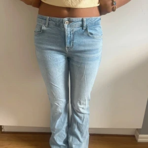 Bootcut ljusblå jeans från Zara - Säljer ett par ljusblå bootcut jeans från Zara i storlek 38. Normal passform och är tillverkade i jeansmaterial. De har låg midja och lite slitna detaljer vid benslutet men inget man tänker på. 