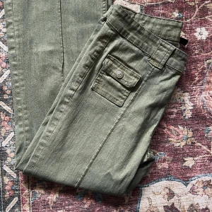 Olivgröna jeans - Snygga olivgröna cargopants från DIVIDED med bootcut model och praktisk ficka med knapp på sidan. Perfekta för en chill och avslappnad stil.