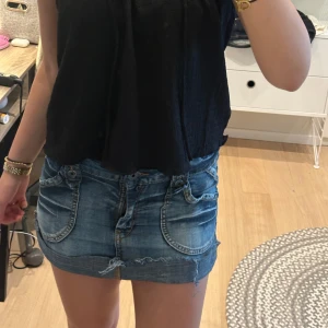 Blå jeansshorts med rå kant - Säljer kjol med låg midja och rå, fransig kant. Shortsen har stora framfickor, slitningar och klassiska bakfickor. Perfekta för dig som gillar en chill och avslappnad stil på sommaren. 