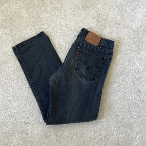 Levi's 505 svarta straight jeans - Svarta Levi's 505 jeans med klassisk femficksdesign och rakt ben. Jeansen har en mörk tvätt och tydlig Levi's-lapp bak i midjan. Materialet är slitstarkt denim i bomull och passformen är straight, vilket ger en chill och tidlös look.