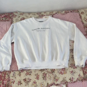 Vit sweatshirt Nouvelle Aquitaine - Vit sweatshirt med tryck 'Nouvelle Aquitaine Bordeaux, France Port de la Lune' på bröstet. Klassisk rund hals och ribbade muddar vid ärmslut och nederkant. Perfekt för chill dagar och enkel att matcha med jeans eller leggings. Knappt använd. Vill bli av med så fort som möjligt så pris kan diskuteras💕