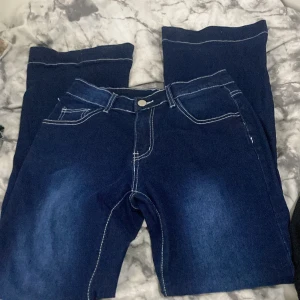 Mörkblå jeansbyxor med kontrastsömmar - Snygga mörkblå jeansbyxor i storlek S med vita kontrastsömmar och klassisk femficksdesign. Byxorna har normal passform och är tillverkade av bomull, polyester och lite elastan för extra stretch. Perfekta för dig som gillar stilrena och bekväma jeans. Från SHEIN