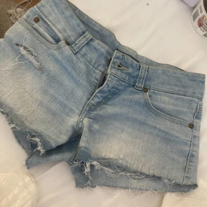 Ljusa jeansshorts från ONLY - Säljer ett par ljusblå jeansshorts från ONLY med fransig och rå kant nertill. de är lågmidjade och nästan aldrig använda shortsen är i storlek xs-s