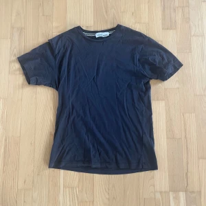 Mörkblå Stone Island t-shirt - Snygg mörkblå t-shirt från Stone Island med klassisk rund hals och korta ärmar. På ryggen finns ett stort tryck med Stone Island-loggan i ljusgrått. T-shirten är gjord i mjuk bomull och har en clean, normal passform som funkar till jeans eller shorts.