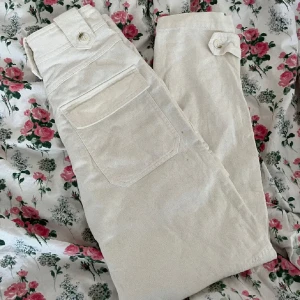 Vita cargobyxor - Ett par vita cargobyxor med högmidja och flera fickor samt knappdetaljer från H&M i strl 32!💞