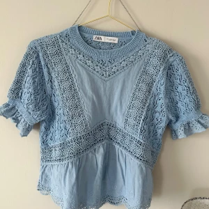 Blå blus från Zara - Supersöt ljusblå blus från Zara med spetsdetaljer och volangkant. Super fin till både vardags och fest tillfällen. Köpt för 400 men använd fåtal gånger 