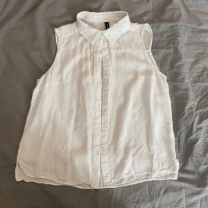 Ärmlös blus - Säljer en vit blus från H&M i storlek 34. Den är ärmlös med klassisk krage och knäppning framtill. Skriv om du har frågor och läs helst min bio innan du köper🫶🏻🫶🏻