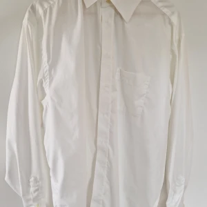 Vit skjorta från Eton - Klassisk vit skjorta från Eton i 100% bomull med bröstficka och knappar framtill. Skjortan har lång ärm och stilren design, perfekt för en dressad look. Märkt som wrinklefree cotton för extra bekvämlighet.