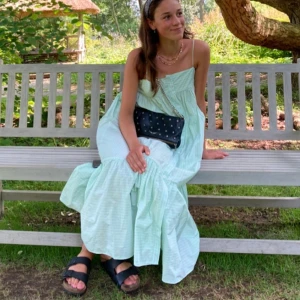 Ljusgrön randig maxi dress från Zara - Säljer en ljusgrön långklänning från Zara med vita ränder. Klänningen har knappar framtill och är ärmlös. Perfekt för sommarens alla tillfällen!! En knapp saknas där uppe se bild 3, men kan verkligen användas ändå!!