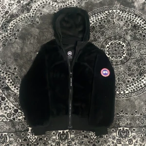 Fleece Canada Goose - Säljer en svart fleece kofta från Canada Goose med huva och dragkedja framtill. Helt otrolig kofta, sällsynt edition samt extremt varm och jätte fluffig 🤗 