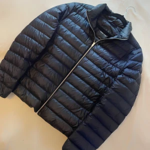 Marinblå pufferjacka från Massimo Dutti - Säljer en riktigt snygg och skön pufferjacka från Massimo Dutti med silvrig dragkedja framtill och hög krage. Jackan har en klassisk quiltad design och är perfekt för kyligare dagar. Enkel och stilren modell som passar till mycket. Köpt nyligen kollektionen slutsåld, 