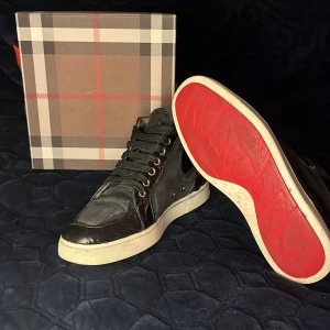 Louboutin skor - Säljer ett par svarta Louboutin sneakers med glansiga detaljer och klassisk vit sula. Skorna är i helt okej skick med några skavanker men inget som syns vid användning. Självklart i skorna äkta och äkthet bevis kan tas fram. Skorna ligger på ungefär 9000 nypris medan jag säljer dem för endast 2299. Har ni några ytterligare frågor bara att höra av er? Med vänliga hälsningar Oscar