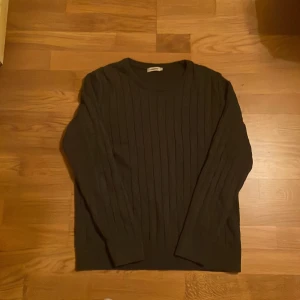 Mörkgrå stickad tröja från J.Lindeberg - Säljer en mörkgrå stickad tröja från J.Lindeberg. Tröjan har lång ärm, rund halsringning och ett diskret ribbat mönster längs hela plagget. Perfekt för lager-på-lager och enkel att matcha med olika outfits.