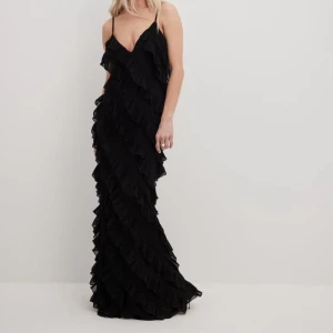 Svart långklänning med volanger - Säljer en svart långklänning med tunna axelband och v-ringning. Klänningen har volangdetaljer över hela och en elegant, flowy siluett. Perfekt för dem lite uppklädda tillfällena! Använd en gång💗Kan skicka egna bilder vid önskemål.