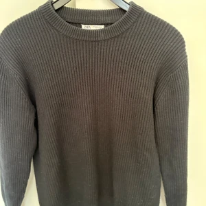 Svart  ribbstickad tröja från Zara - En stilren svart  ribbstickad tröja från Zara med rund halsringning. Tröjan har lång ärm och är perfekt för lager-på-lager. Enkel och klassisk design som passar till mycket.