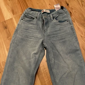 Levi's Stay Loose ljusblå jeans - Säljer ett par ljusblå Levi's Stay Loose jeans med klassisk femficksdesign och raka, vida ben. Jeansen har knappgylf och tydlig Levi's patch bak i midjan. Perfekta för en avslappnad och trendig look.