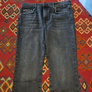 Svarta jeans från Gina - Säljer ett par svarta jeans från Gina med klassisk femficksdesign och råa, fransiga benslut. Jeansen har normal passform och är tillverkade i ett stretchigt denimtyg. Perfekta till vardags och enkla att matcha med olika toppar.