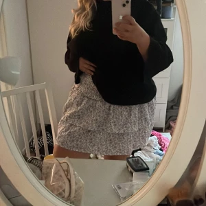 Blommig kortkjol från DWS Alva - Supersöt kortkjol från bikbok med blommigt mönster i lila, rosa och blå toner på ljus botten. Kjolen har en avslappnad passform och resår i midjan för extra komfort. Perfekt att styla med en enkel topp eller stickad tröja.