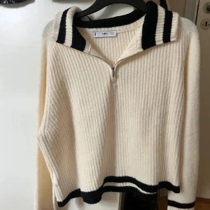 Vit stickad tröja med dragkedja  - Säljer nu min fina vit stickade tröja från mango som är helt slutsåld. Den har svarta ränder på krage, ärmslut och nederkant. Super skönt material och perfekt nu till sena sommar kvällar! Hör av er vid frågor 😊
