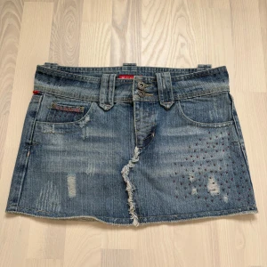 Jeanskjol med unika detaljer🌸 - Kort jeanskjol från Influence med slitna detaljer och dekorativa pärlor. Fickor både fram och bak, varav en bakficka har broderat hjärta. Två knappar i midjan och breda hällor🩷. Köpt secondhand men aldrig använd av mig då den tyvärr är för liten. Hör av dig vid frågor💕🌸