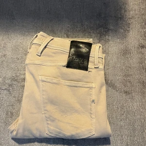 Beige Replay Anbass jeans - OBS Priset ej hugget i sten. Säljer ett par snygga beige Replay Anbass jeans med klassisk femficksdesign och diskreta detaljer. Byxorna har tight passform och är tillverkade i ett stretchigt material för extra komfort. Perfekta för dig som vill ha stilrena och bekväma jeans. 