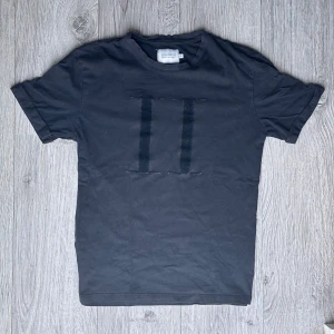 Les Deux T-Shirt - Black - Svart T-shirt från Les Deux. Flockad logga på framsidan. Mycket stilren tröja, alltid varit nöjd med denna. Säljer då den är för liten för mig. Passar Small till Medium.