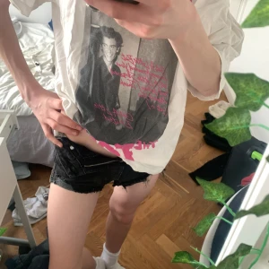 Vit Shawn Mendes tour t-shirt - Vit t-shirt med stort tryck av Shawn Mendes och rosa text framtill. Oversized passform och tillverkad i bomull. Perfekt för dig som gillar bandtröjor och vill ha en cool och avslappnad stil.