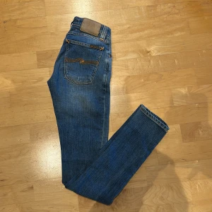 Blå jeans från Nudie Jeans - Ett par ljus blå nudie jeans med inget slitage. Byxorna är raka i benen och har en slim fit.